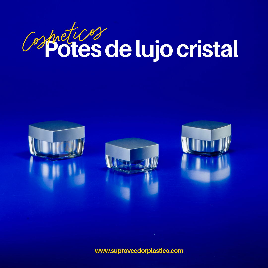 Tres potes cosméticos cuadrados de lujo con base transparente de paredes gruesas y tapa plateada satinada, sobre un fondo azul. Envase para crema de ojos.